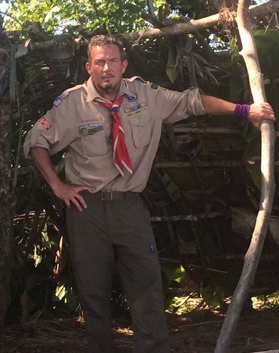 Terry L. Fossum in his Scoutmaster uniform beside a survival shelter he built on Fox's Kicking & Screaming
